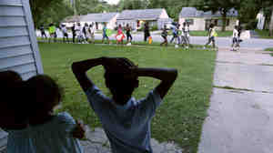Children watch from their home in Ferguson, Mo., on Aug. 20 as people march about a mile to the police station to protest the shooting of Michael Brown. Brown's shooting in the middle of a street by a Ferguson police officer on Aug. 9 sparked protests, riots and looting in the St. Louis suburb. Some people are ready to leave the troubled city. Others say they will remain no matter what.