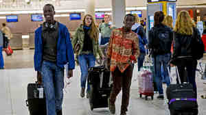 Thomas Nellon (left), 17, and his brother Johnson Nellon, 14, of Liberia smile at their mother in the arrivals area at John F. Kennedy International Airport in New York earlier this month. The brothers received a health screening upon arrival. The U.S. says it will step up screening measures for arrivals from Ebola-affected West African countries.