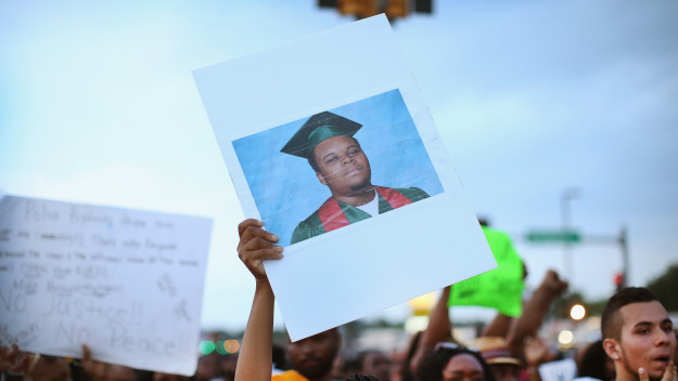 A demonstrator carries a picture of Michael Brown during a protest along Florissant Avenue on August 16, 2014 in Ferguson, Missouri. Violent protests have erupted nearly every night along the street since the shooting death ofl Brown by a Ferguson police officer on August 9. (Photo by Scott Olson/Getty Images)