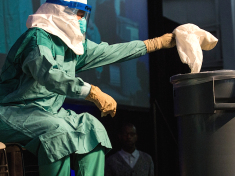 A nurse demonstrates how to properly put on protective medical gear when working with someone infected with the Ebola virus. (credit:  Andrew Burton/Getty Images)