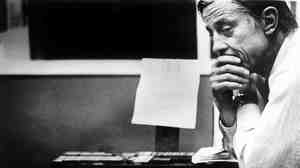 Ben Bradlee, then-executive editor of The Washington Post, looks at the front page of the newspaper, headlined "Nixon Resigns," in the composing room on Aug. 8, 1974.