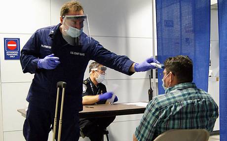 U.S. Coast Guard Health Technician Nathan Wallenmeyer (left) and Customs and Border Protection supervisor Sam Ko conduct prescreening measures on a passenger arriving from Sierra Leone at O'Hare International Airport's Terminal 5 in Chicago. The Centers for Disease Control and prevention said Wednesday that 21-day Ebola monitoring will now be required for all travelers from West Africa, including visitors and returning Americans.