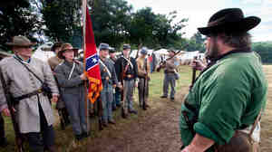 Waverly Adcock, a sergeant and founder of the West Augusta Guard, prepares his company for inspection and battle at a Civil War re-enactment in Virginia. Sara Smith, whose great-great-grandfather was wounded at the Battle of Gettysburg, holds the Confederate battle flag.