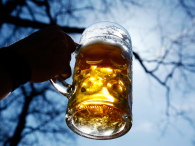A man raises a mug of beer. (credit: Getty Images/Sebastian Widmann/AFP)