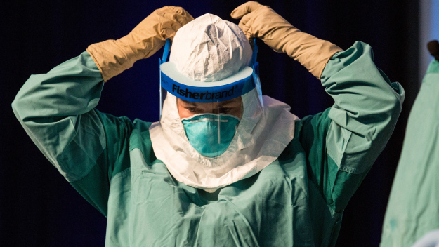 Barbara Smith, a nurse with Mount Sinai Health System, demonstrates to health care professionals how to properly put on protective medical gear when working with someone infected with Ebola at the Javits Center on Oct. 21, 2014. The outfit includes two pairs of gloves, mesh breathing mask, protective hood, plastic face shield, booties, liquid resistant gown and sanitizer. (Photo by Andrew Burton/Getty Images)