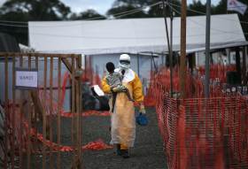 A Doctors Without Borders health worker in protective clothing carries a child suspected of having Ebola in the MSF treatment center on Oct. 5, 2014 in Paynesville, Liberia.