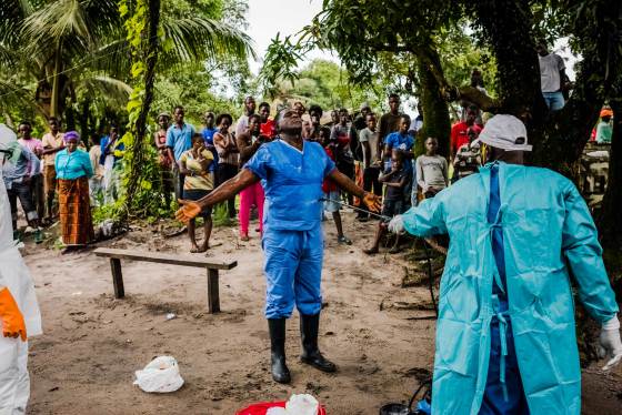 A member of a Liberian Red Cross burial team is disinfected, with chlorine sprayed on by a colleague, after having removed the body of a man, a suspected Ebola victim from his home on Sept. 6, 2014 in Monrovia, Liberia.