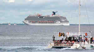 The cruise ship Carnival Magic floats behind a catamaran off Cozumel, Mexico on Oct. 17. The ship skipped a planned stop there Friday, the cruise line says, after Mexican authorities delayed granting permission to dock.