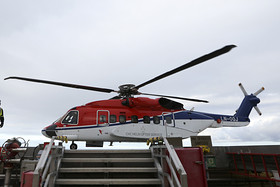 An employee stands beside a Sikorsky Aircraft Corp. S-92 helicopter operated by CHC Helicopter Services on the helipad at the Troll A offshore gas platform, operated by Statoil ASA, in the North Sea Troll near Bergen, Norway, on Thursday, Oct. 11, 2012. Statoil is holding talks with OAO Gazprom on how to make the Shtokman natural gas project in the Russian Arctic economically viable after the partners delayed the development over costs. Photographer: Chris Ratcliffe/Bloomberg