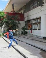 A masked protester hurls a rock at windows in the city hall in Iguala, Mexico, on Wednesday. Minutes later, marauders set the building afire.