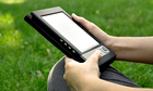 Young woman reads electronic book sitting on the grass. Shallow depth of field.