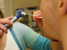 A family doctor checks a patient's mouth and throat. (credit: Sean Gallup/Getty Images)