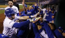 Mike Moustakas es felicitado por sus compañeros juego de conectar un jonrón para los Royals en el Juego 6 de la Serie Mundial.