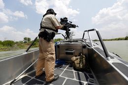 A Texas Parks and Wildlife Warden stands next to a 30 caliber rifle as he patrols the Rio Grand on the U.S.-Mexico border , Thursday, July 24, 2014, in Mission, Texas. Texas is spending $1.3 million a week for a bigger DPS presence along the border.