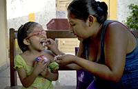 A mother giving her child TB medication, Peru.