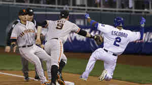The San Francisco Giants' Brandon Belt can't reach the Kansas City Royals' Alcides Escobar as he slides safely to first base on an infield single Tuesday night during the second inning of Game 6 of baseball's World Series in Kansas City, Mo. Escobar eventually would score the Royals' fourth run.