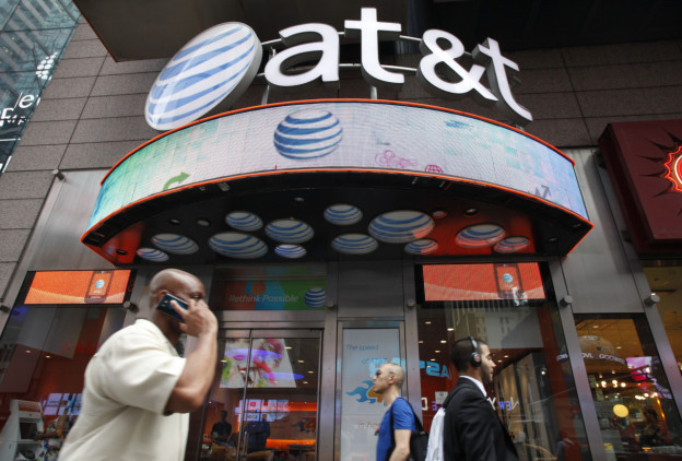 A man uses a cell phone as he walks past an AT&T store in New York, July 11, 2013. (Mark Lennihan/AP)