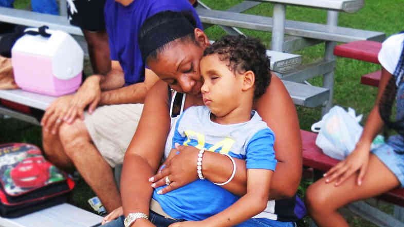 Five-year-old Kyle Romain sits on the lap of his grandmother, Barbara Romain, at a football game. Kyle lost his sight when he was hit by a stray bullet two months ago.