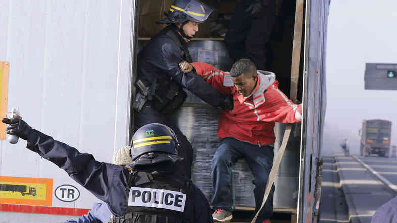 French riot policemen force out migrants who were hidden in a truck that was making its way to the ferry terminal in Calais in western France on Wednesday. The cross-Channel port has become the last barrier for economic and political migrants trying to enter Britain illegally.