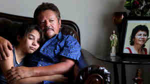 Guillermo Gomez, husband of Vilma Marenco, holds his daughter in their home in Northeast Houston. Marenco was killed in April after being hit by an uninsured trucker who ran a red light.