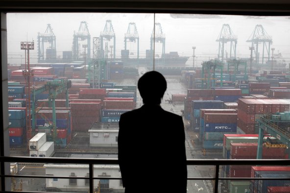 An employee viewing the Port of Shanghai, the world's busiest, from an office window.