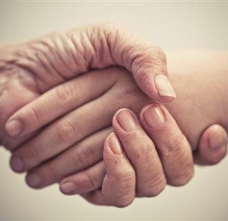 Elderly and younger person shake hands