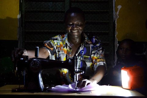 A man in Tanzania operating a sewing machine by the light of <a href="http://rendezvous.blogs.nytimes.com/2012/12/31/bringing-sunlight-to-africa-and-western-investors/">a rechargeable solar LED lamp</a>.