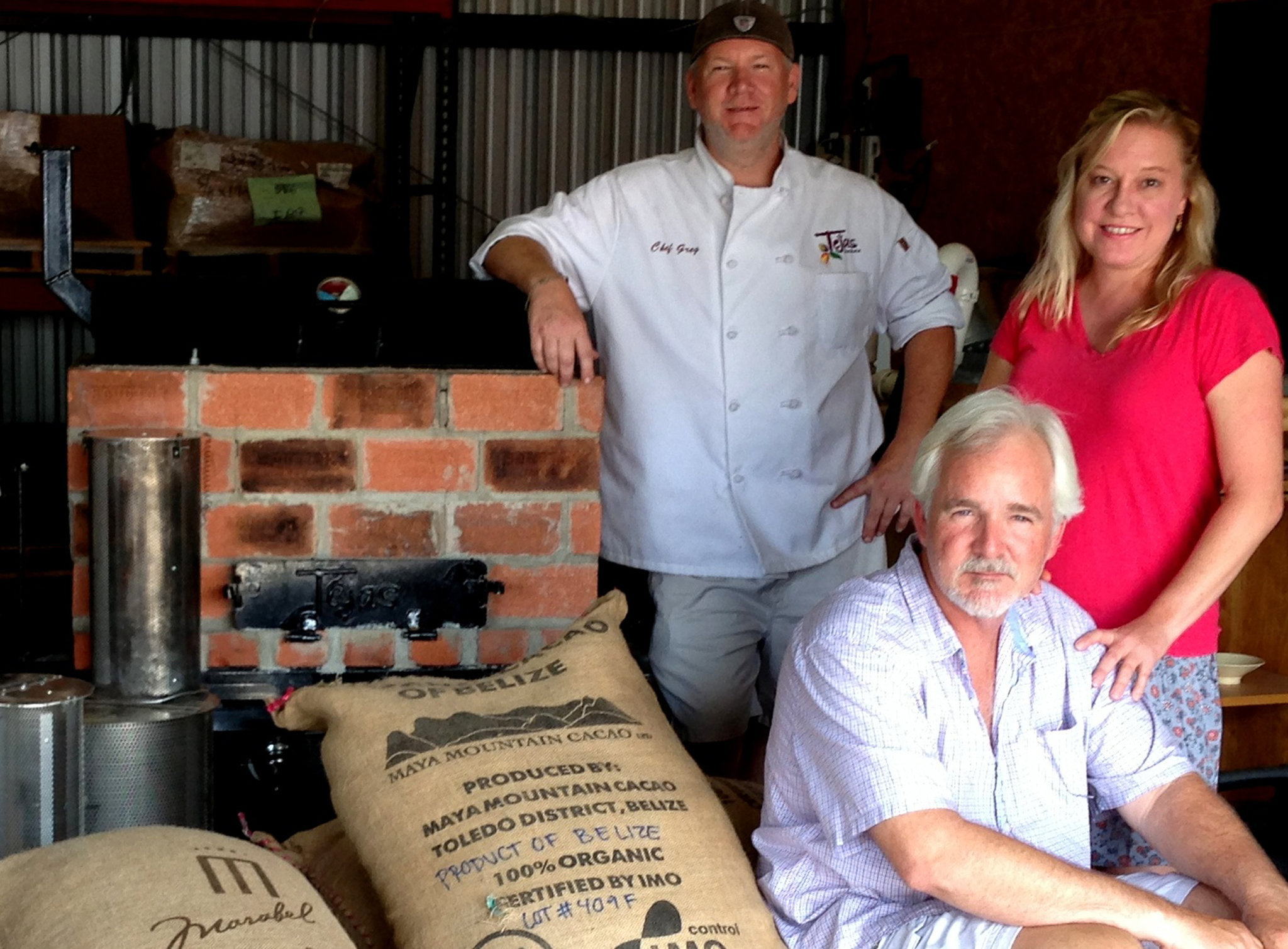 Greg Moore, Michelle Holland and Scott Moore next to the pit they use for roasting cacao beans. 