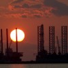 The sun sets behind two under construction offshore oil platform rigs in Port Fourchon, Louisiana, June 14, 2010, as cleanup continues on the BP Deepwater Horizon oil spill.