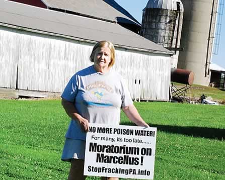 photo of a woman holding a protest sign on a farm