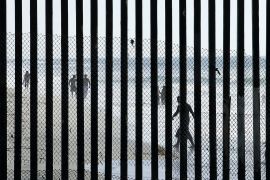People walk along the beach in Tijuana, Mexico, where metal bars marking the border with the United States meet the sea Wednesday, Oct. 29, 2014, as seen from San Diego.  (AP Photo/Gregory Bull)