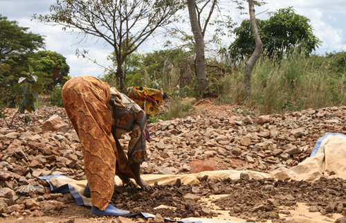 A woman spreads out gold ore in the sun to dry. Photo:Marc Choyt