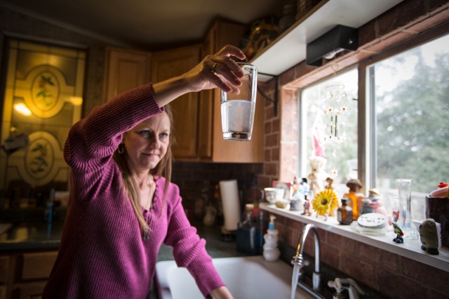 Shelly Perdue holds up contaminated water in her Granbury, Texas, kitchen. Her home is across the street from a Range Resources fracking site. ©2014 Julie Dermansky