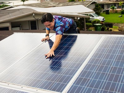 Attorney Isaac Moriwake examines solar panels installed on his rooftop. (Matt Mallams / Earthjustice)