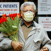 A man wears a protective mask as he carries a bouquet of flowers at Women's College Hospital in Toronto in March 2003, when SARS fears about were widespread.