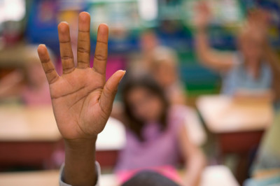 Students raise their hands in class. (Getty Images)