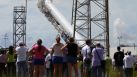 CAPE CANAVERAL, FL - OCTOBER 07:  People watch as a SpaceX Falcon 9 rocket attached to the cargo-only capsule called Dragon is raised into launch position as it is prepared for a scheduled evening launch on October 7, 2012 in Cape Canaveral, Florida. The rocket will bring cargo to the International Space Station that consists of clothing, equipment and science experiments. SpaceX is weighing South Texas as a potential spot to launch commerical rockets. (Photo by Joe Raedle/Getty Images)