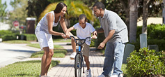 image of parents teaching child to ride bike