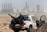 An anti-government rebel sits with an anti-aircraft weapon in front an oil refinery, after the capture of the oil town of Ras Lanouf, eastern Libya. (AP Photo/Hussein Malla, File)