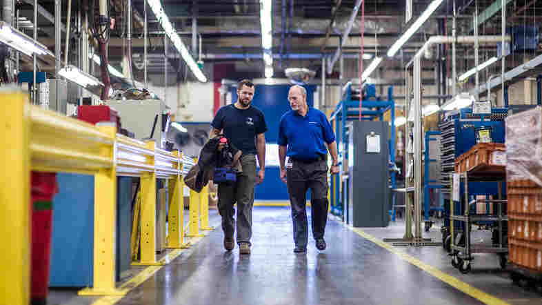 John Harris (left) walks with Warren Snead, a manager for Cooper Standard, an auto parts manufacturing factory near Spartanburg, S.C. After working as an electrician in the Air Force, Harris found the apprenticeship program at Cooper Standard, where he learns while working on the job.