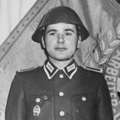 Harald Jaeger in uniform next to the flag of his East German border regiment in 1964.