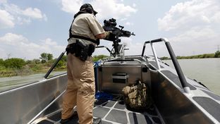 A Texas Parks and Wildlife Warden stands next to a 30 caliber rifle as he patrols the Rio Grand on the U.S.-Mexico border , Thursday, July 24, 2014, in Mission, Texas. Texas is spending $1.3 million a week for a bigger DPS presence along the border.