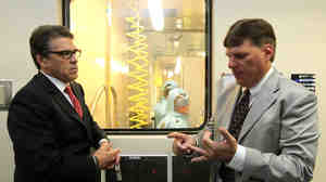 Texas Gov. Rick Perry (left) listens to Tom Geisbert, a professor of microbiology and immunology at the University of Texas Medical Branch, explain the work researchers are conducting in a lab in the Galveston National Laboratory on Tuesday. Numerous Republicans, including Perry, have linked the first Ebola case diagnosed in the U.S. to border control and other political issues.