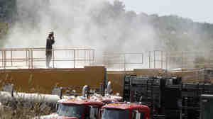 A worker stands on top of a storage bin on July 27, 2011, at a drilling operation in Claysville, Pa. The dust is from powder mixed with water for hydraulic fracturing.