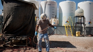 A worker untangles a hose at a Fountain Quail water management and treatment facility in Roanoake, Texas. Fountain Quail cleans and separates water used in fracking for natural gas removal.