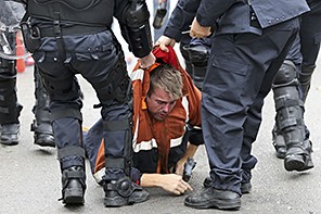 A demonstrator is restrained by riot police during clashes in central Brussels November 6, 2014. Tens of thousands of public and private sector workers, employees and trade union members demonstrated over austerity measures to be taken by the new Belgian government. REUTERS/Yves Herman (BELGIUM - Tags: POLITICS BUSINESS CIVIL UNREST BUSINESS EMPLOYMENT)