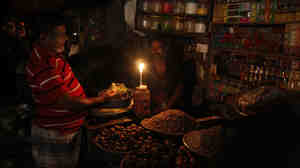 A man sells products by candlelight at a grocery during a blackout in Dhaka, Bangladesh, on Saturday.