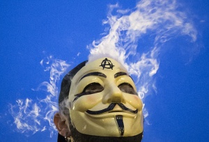 Vapor passes through a Guy Fawkes mask as a man smokes while joining supporters of the Anonymous movement who were taking part in the global Million Mask March protests in Union Square, New York November 5, 2014. REUTERS/Elizabeth Shafiroff
