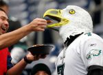 Houston Texans fan Oscar Melendez, left, feeds his friend Jonathan Serrato, wearing a Philadelphia Eagles outfit, a piece of chicken in the stands before the start of an NFL football game at NRG Stadium,Sunday, Nov. 2, 2014, in Houston.