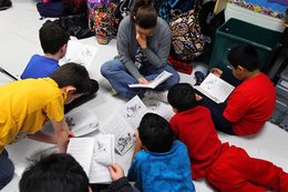 A reading assistant reads on the classroom floor with a small group of fourth graders at Wanke Elementary School in San Antonio on March 9, 2012.